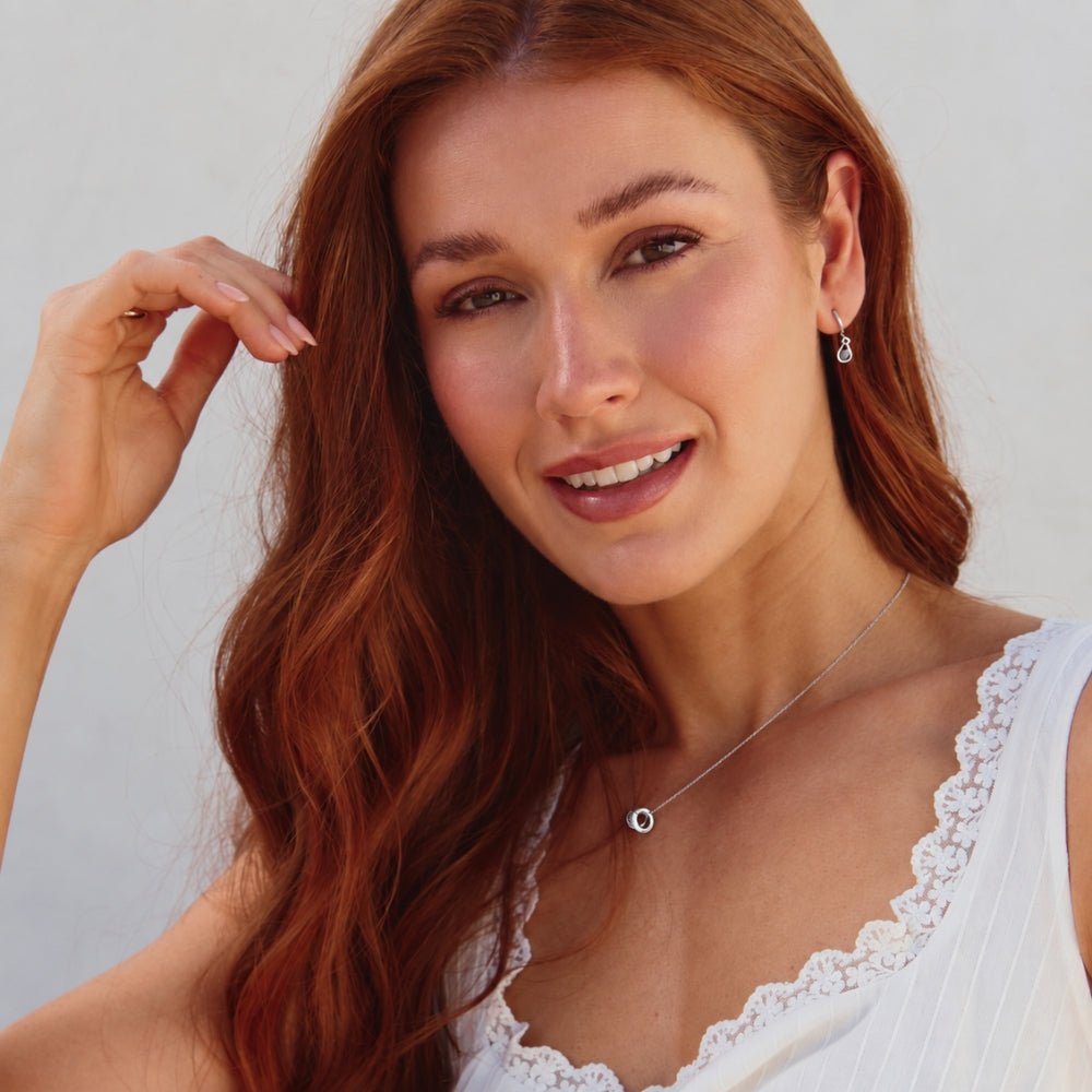 Silver Midnight Teardrop Earrings, worn by a smiling model with a silver pendant necklace