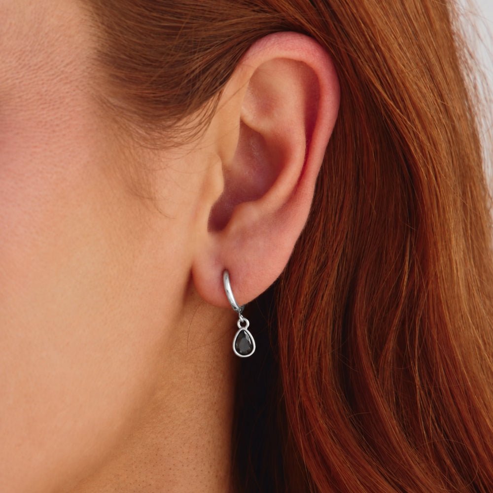 Silver Midnight Teardrop Earrings, worn on an ear with a dark teardrop stone drop